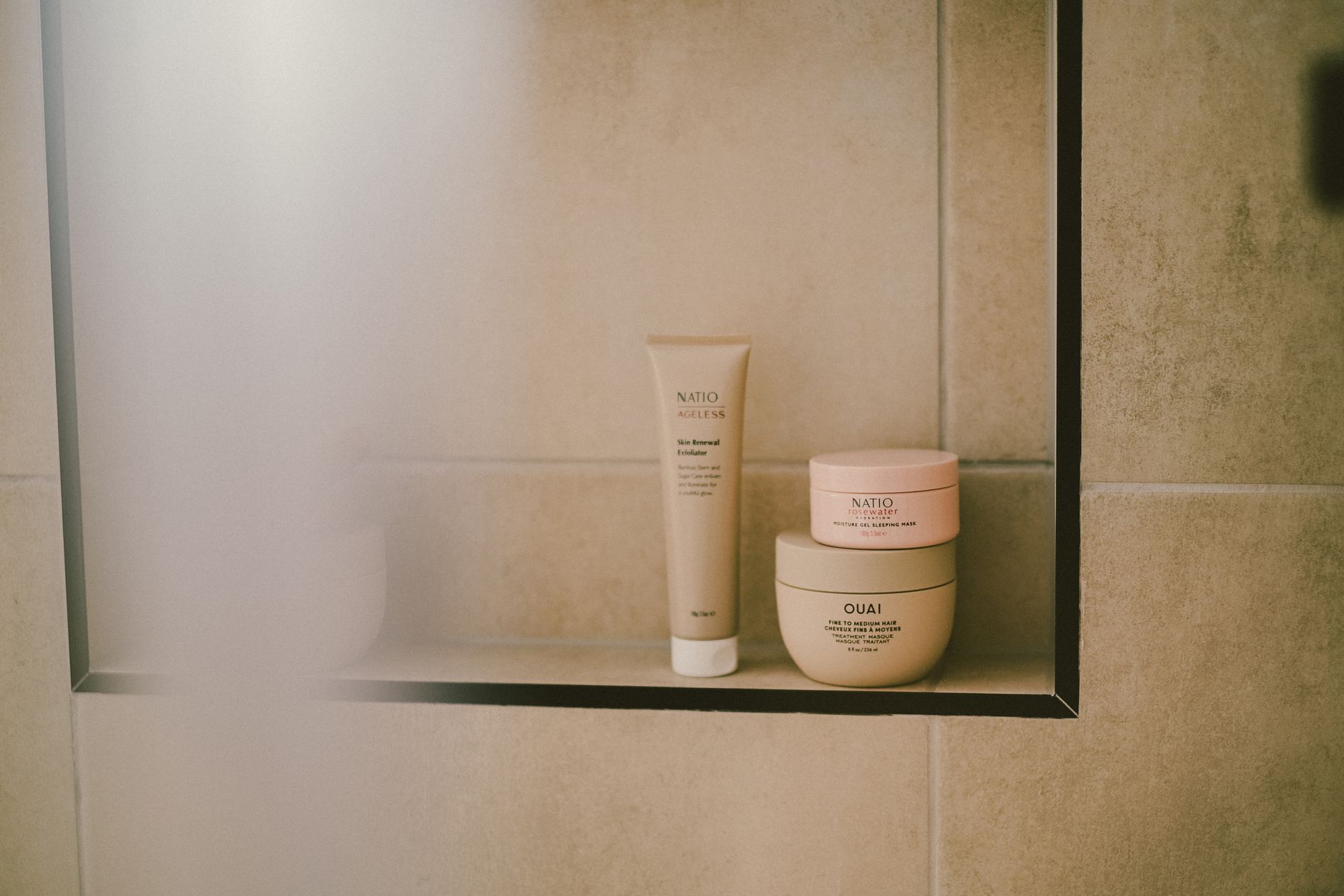 an organized bathroom shelf with natural personal care products in neutral containers