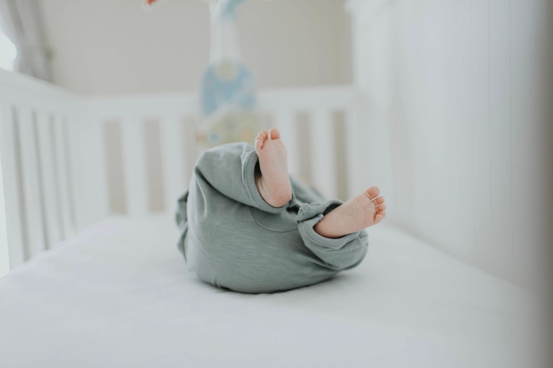 a natural crib mattress with an organic cotton cover inside a nursery