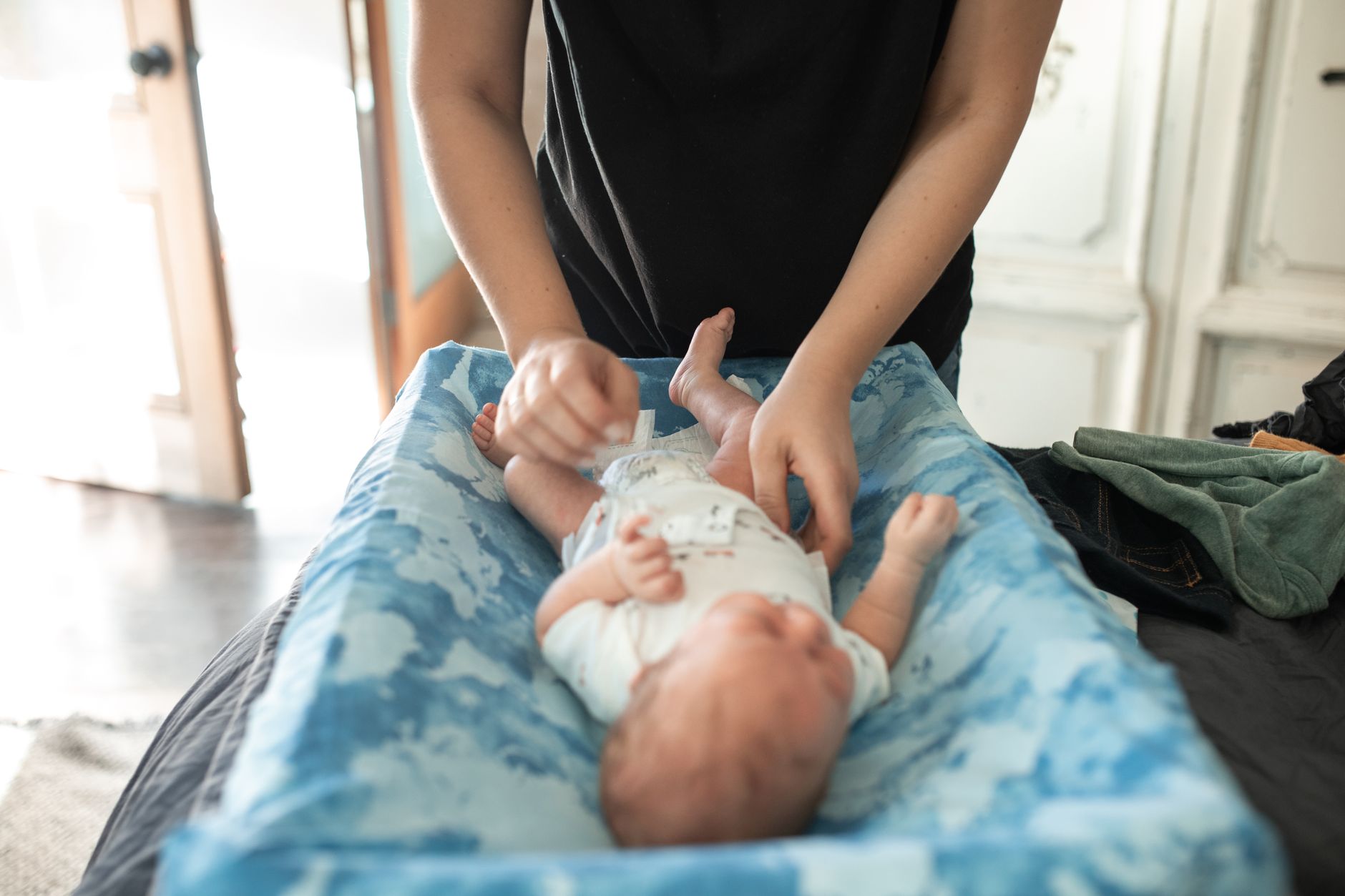 stacked cloth diapers and natural baby wipes on a wooden changing table