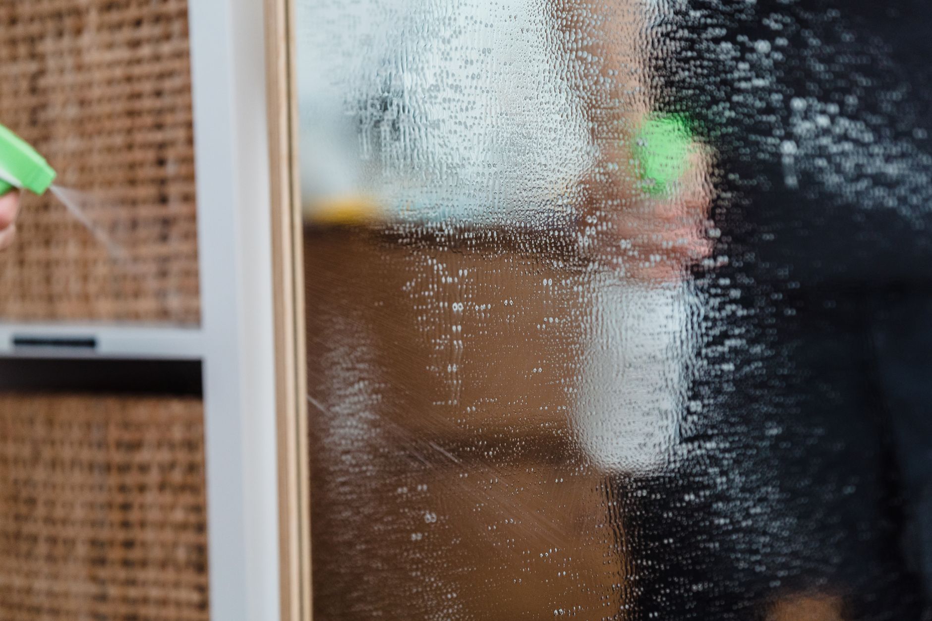 a clear spray bottle filled with plant based cleaner next to a towel on a kitchen counter