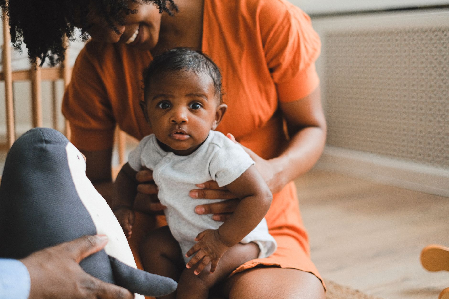 a parent holding a baby near soft toys in a bright nursery