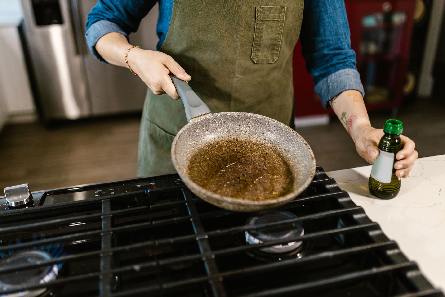 a nonstick frying pan with a colorful exterior sitting on a gas stove burner