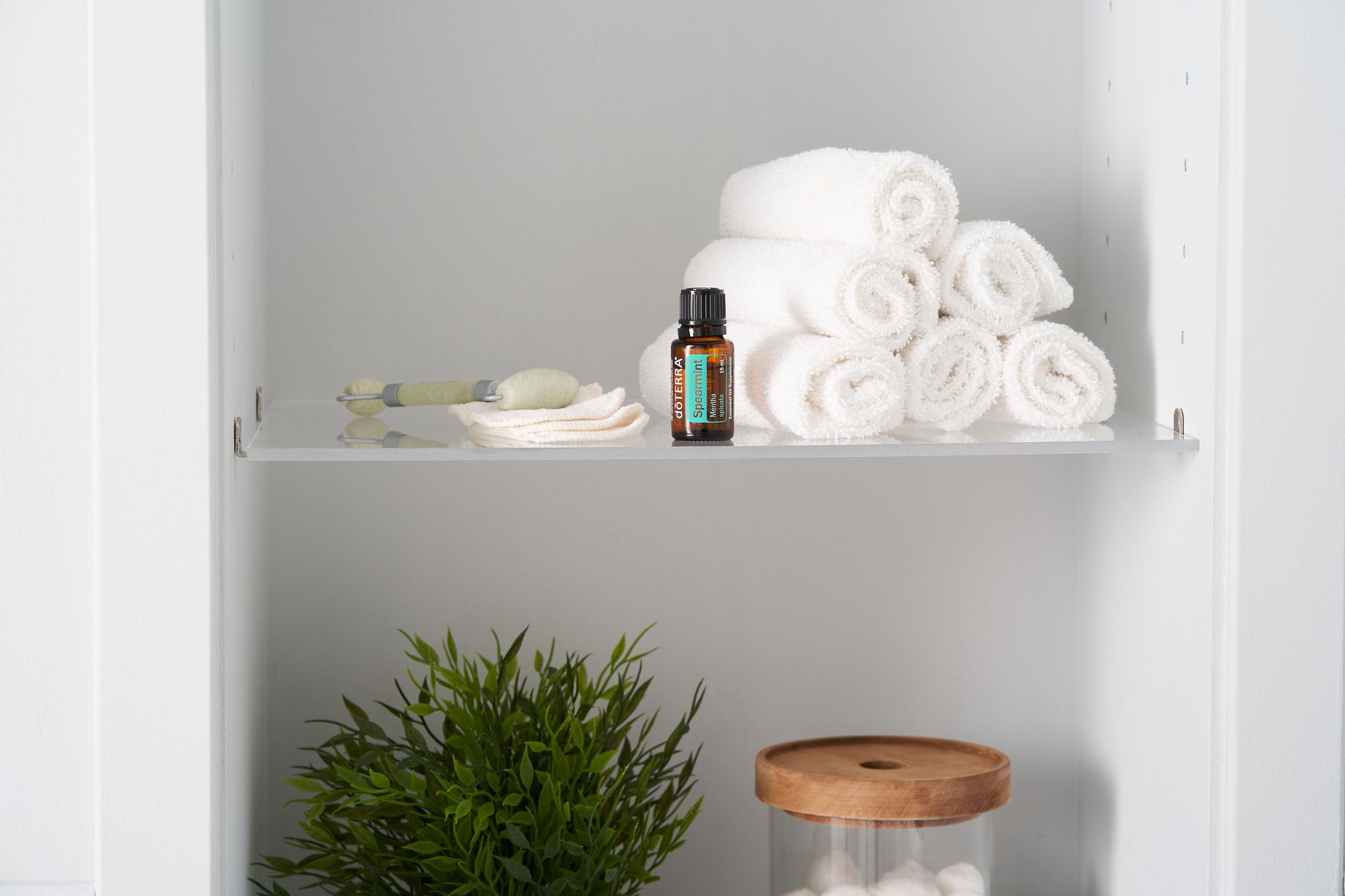 a bathroom shelf holding lotions, cleansers, and folded towels